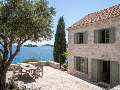 Example apartment: stone house with green shutters and a terrace by the sea