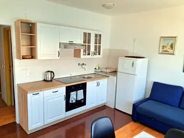 Apartment photo: kitchen with white cabinets and a blue sofa